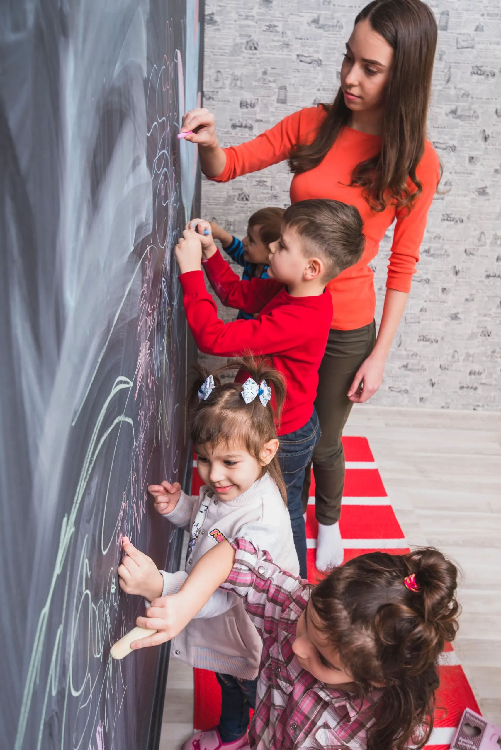 female tutor drawing blackboard with kids scaled